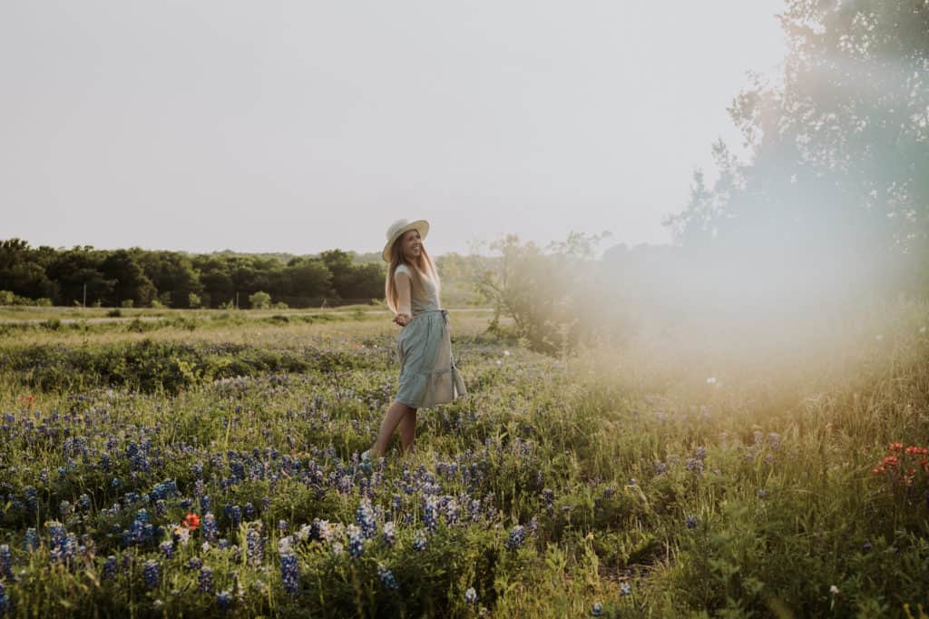 a field of bluebonnets with a girl dancing among the wildflowers