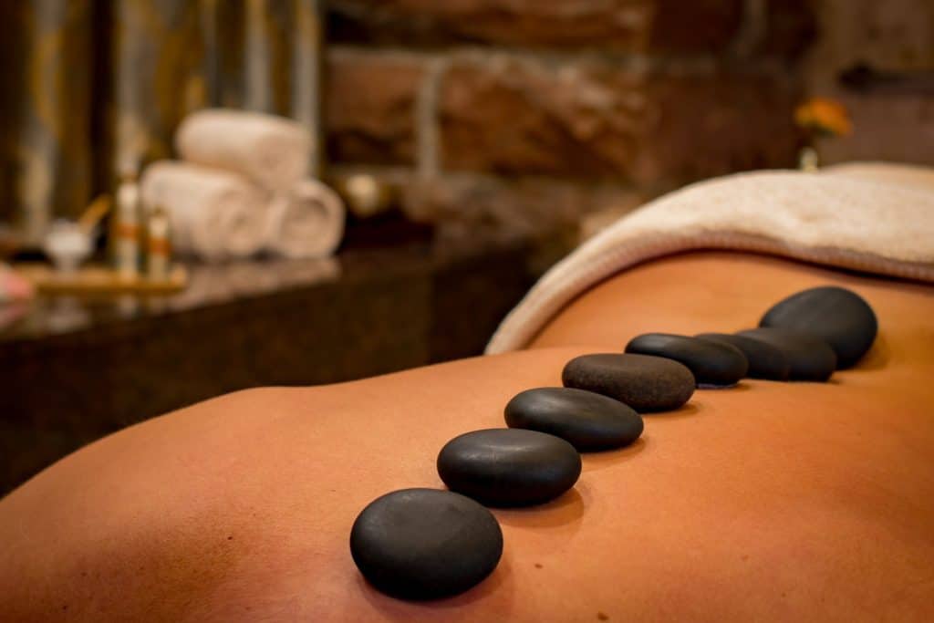 A woman receiving a hot stone spa treatment. Self care is another thing to save up for. Making sure your cup is full so that you can better help others.