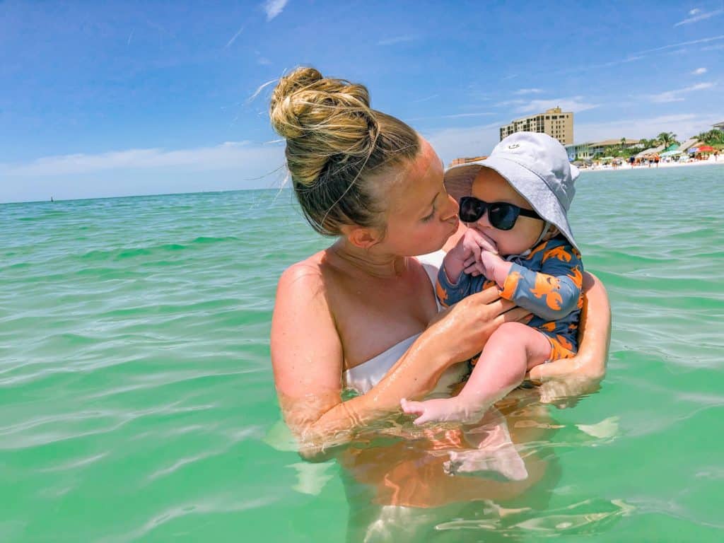 Mom and baby enjoying the emerald green ocean water while at the beach. 
