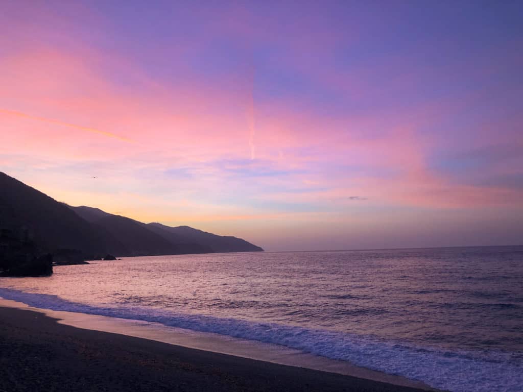 cotton candy colored Sunrise on the beach in Monterosso Italy.