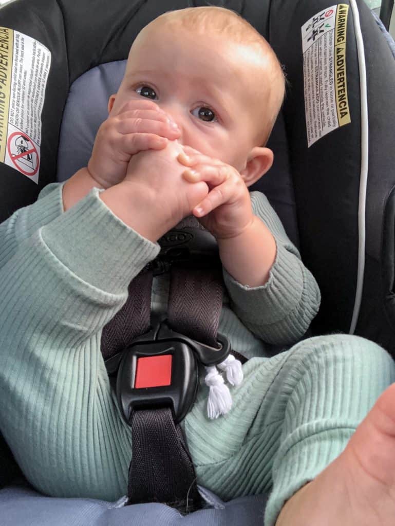 Young baby in a carseat eating his toes. Road tripping with a baby can be done and it doesn't have to be a miserable experience.