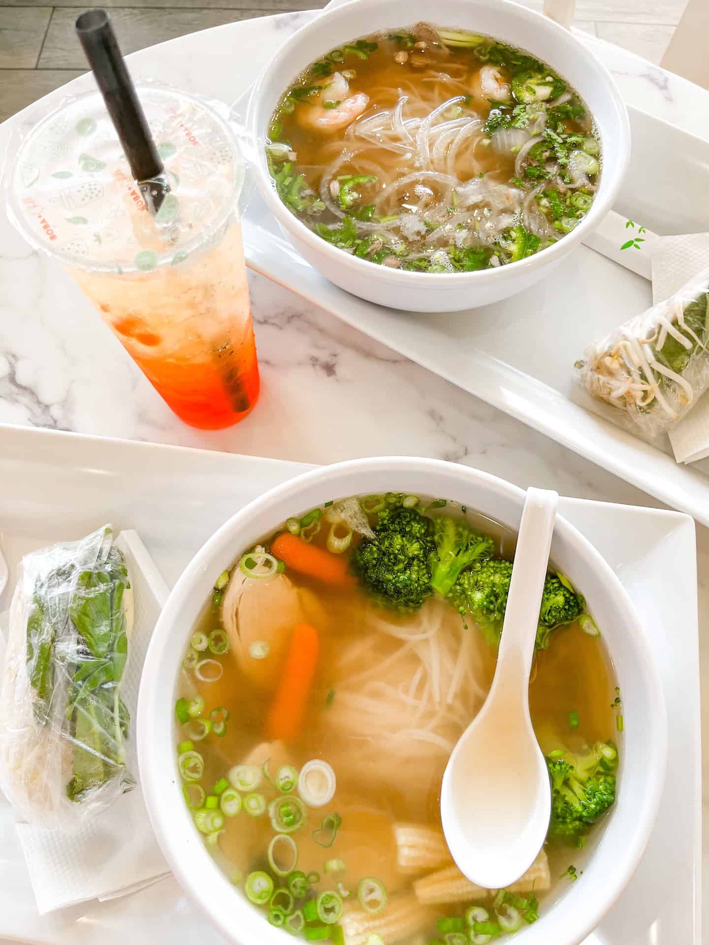 Two bowls of pho and a boba tea.