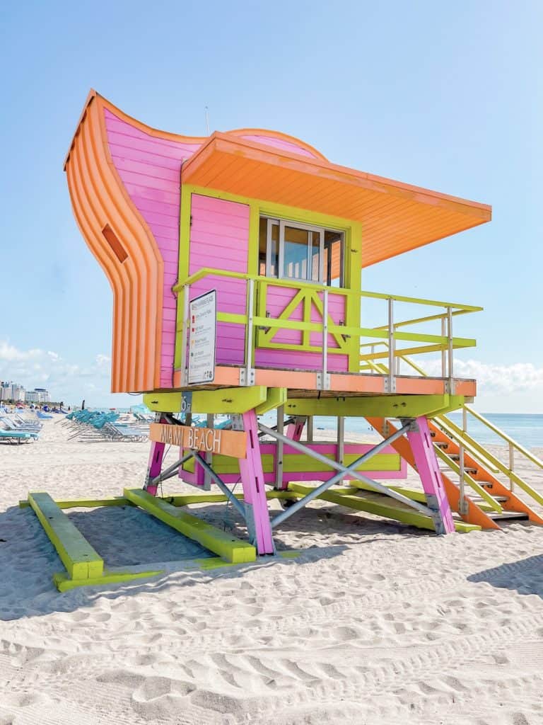 A colorful pink, green and orange lifeguard stand on South Beach in Miami. Hunting for lifeguard stands is a fun way to spend a beach day. A relaxing day at the beach is a must in a 3 day Miami itinerary.