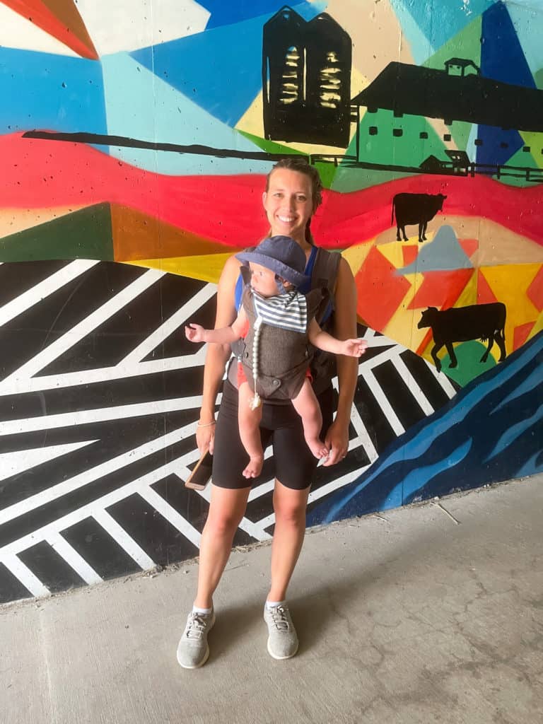 Women holding a baby in a baby carrier while on vacation. A good baby carrier is the number one baby travel essential everyone should have.