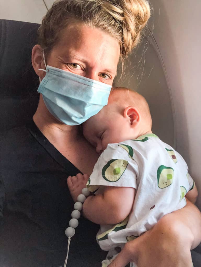 woman holding a sleeping child on an airplane. Baby travel essentials can help make travel with kids as easy as this looks
