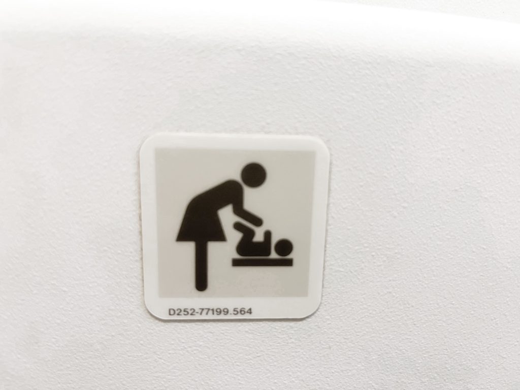 When changing diapers on a plane look for this symbol on bathroom doors to find out which restrooms have changing tables.