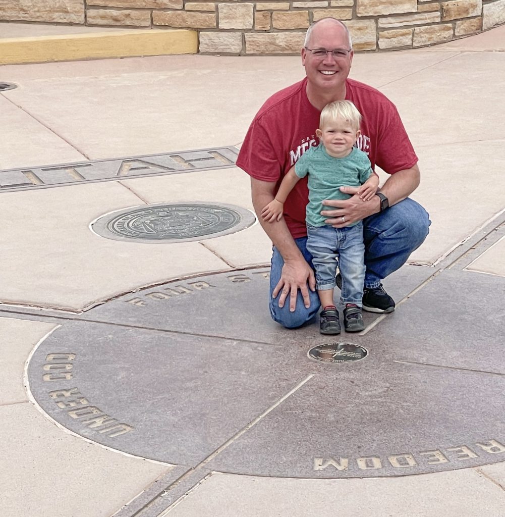 Grandpa and grandson posing on four corners monument. If you are looking for other sights to see near mesa verde, four corners national monument is a great place to visit.