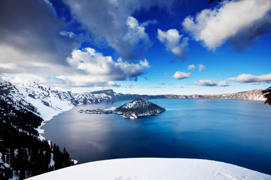 Crater Lake in the winter covered in a thick layer of snow is one of the best winter vacations in the northwestern US for families.