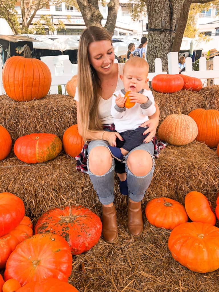 Mom and son sitting on a hay bale surrounded by pumpkins at a free Tampa pumpkin patch