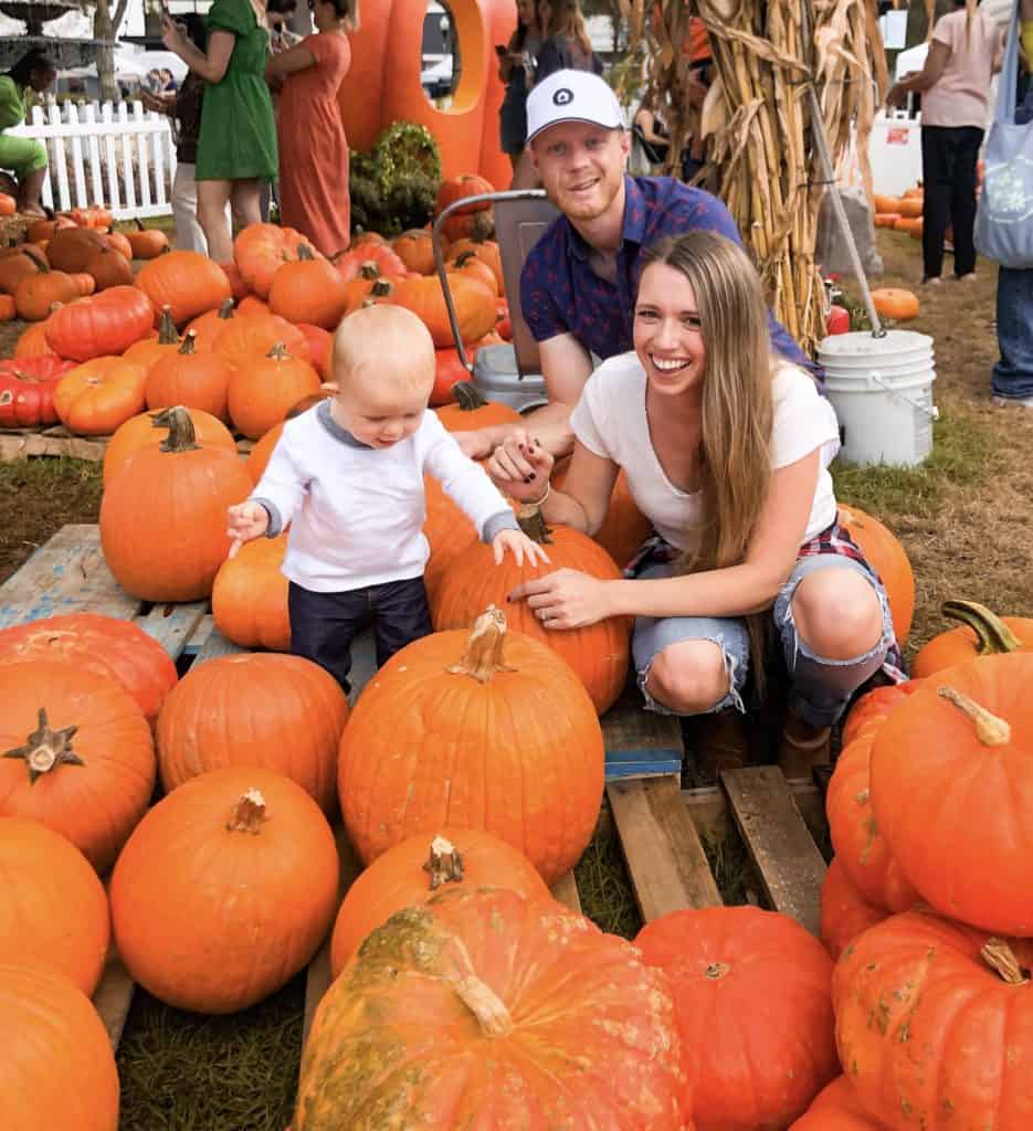 Family of three picking out pumpkins at a pumpkin patch in Tampa.