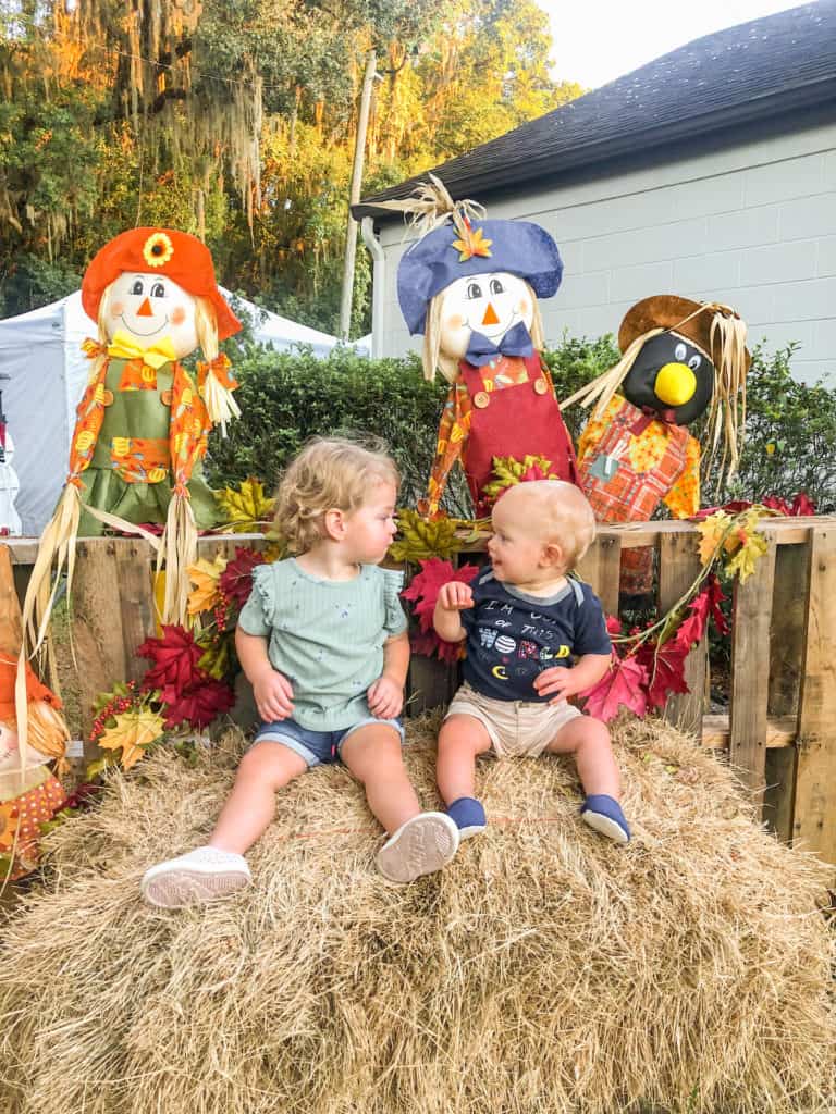 Two young children sitting on a decorated hay bale at a fun fall event for the whole family near Tampa.