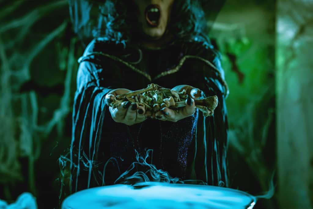 Witch holding bones while making a potion during a haunted house in Tampa.
