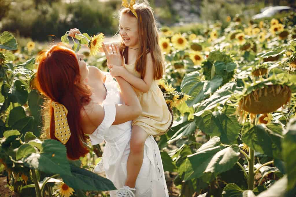 Mother and daughter playing in a sunflower field in Florida while getting family pictures.