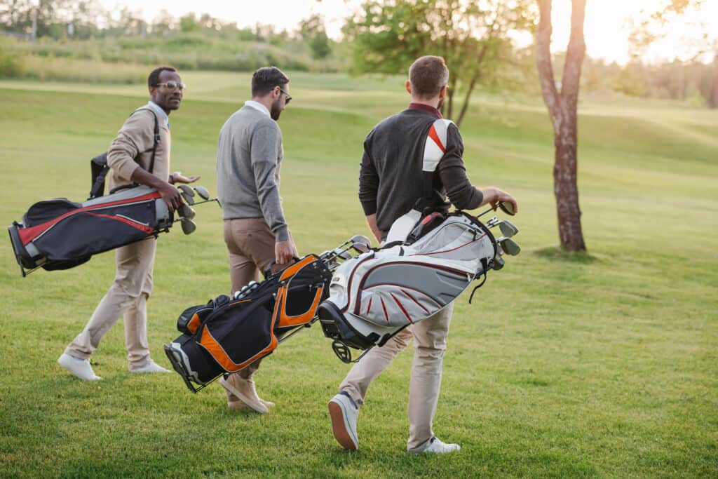Men walking with golf bags on a golf field.