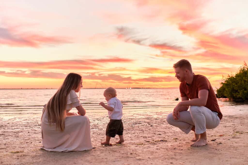 A mother, father and son playing on the beach at sunset in Tampa.