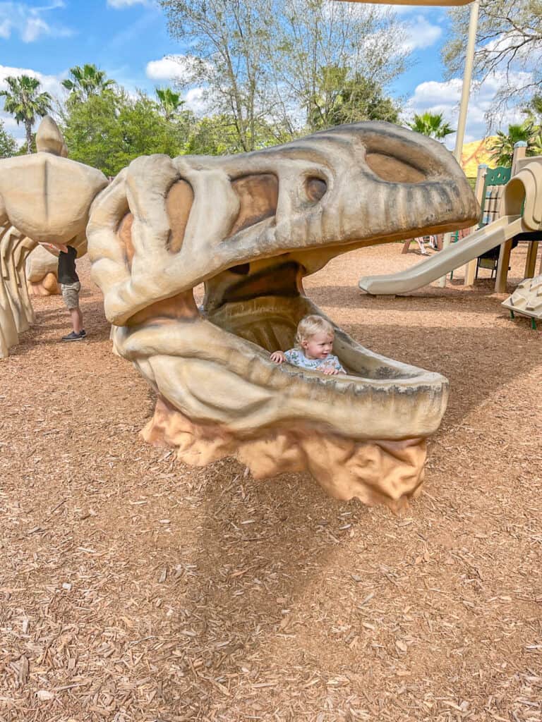 Cute child enjoying the dinosaur themed playground at Dinosaur World in Florida.
