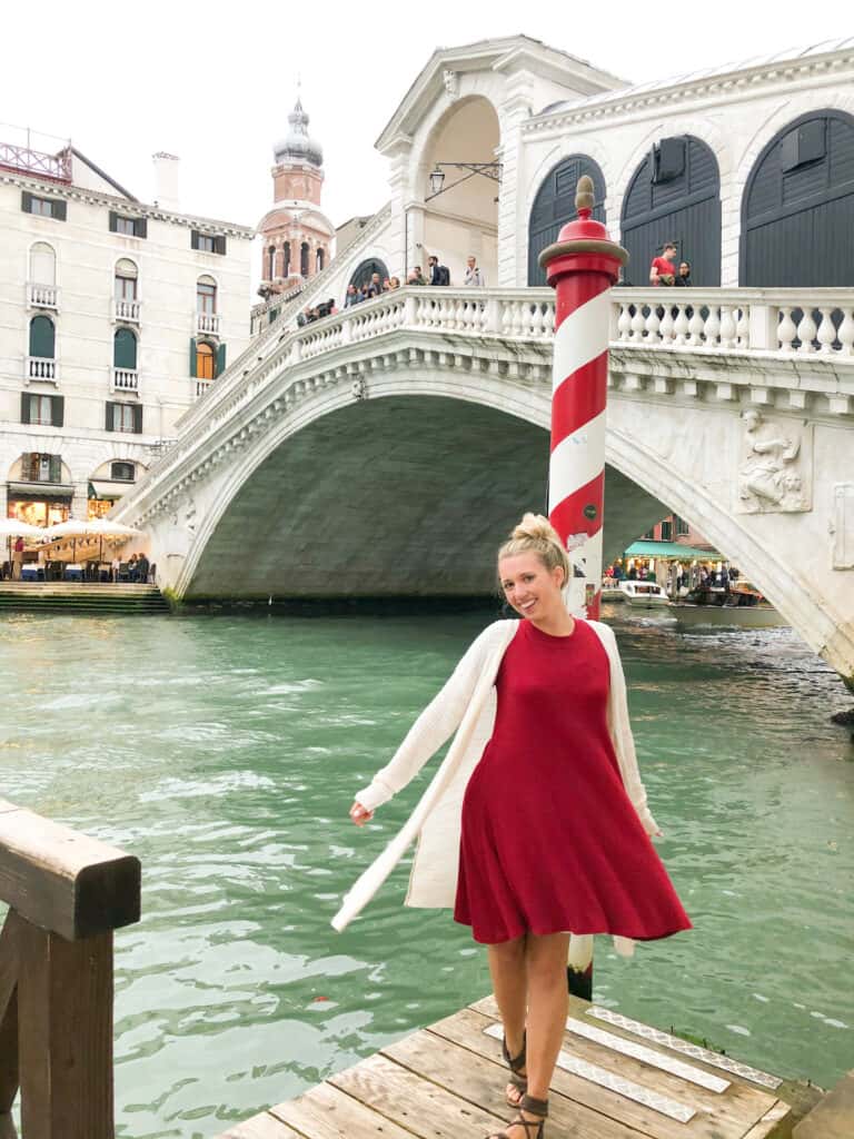 Layers are essential to staying comfortable when you choose what to wear in Rome in October. This woman in Venice is wearing a comfortable red dress and lightweight cardigan.