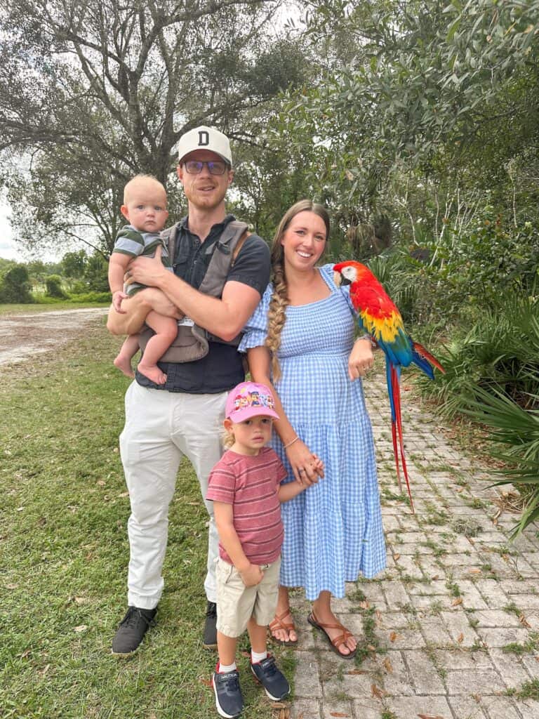 A young family posing with an ambassador bird at bird garden of Naples. A fun activity for a two day itinerary in Naples Florida